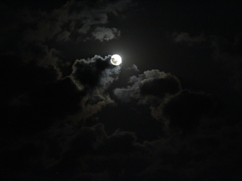 Full moon glowing through clouds at night